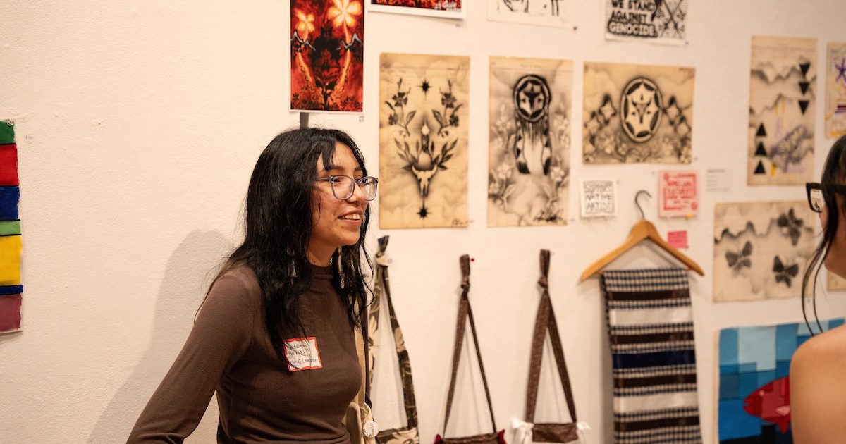 Student presenting her artwork on the wall.