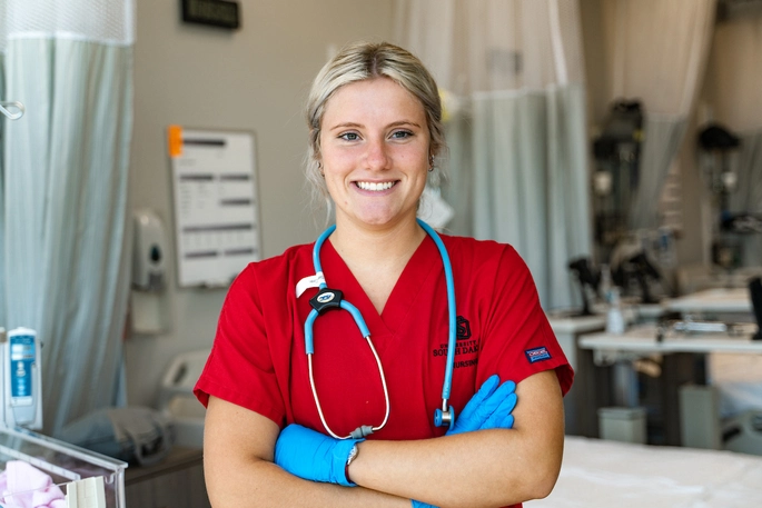 Medical student wearing red scrubs with a stethoscope around her neck.
