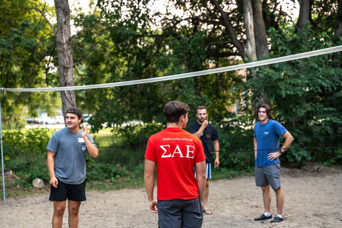 Sigma Alpha Epsilon frat members playing beach volleyball outside.