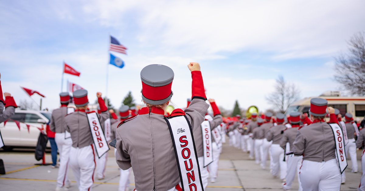 Photo of the backs of USD Alumni Band members marching outside.