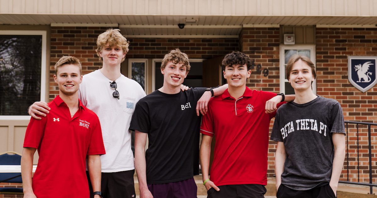 Five members of the Gamma Alpha Chapter of Beta Theta Pi outside of their house.