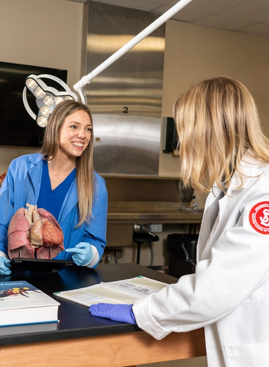 A group of medical students study anatomy in a classroom.