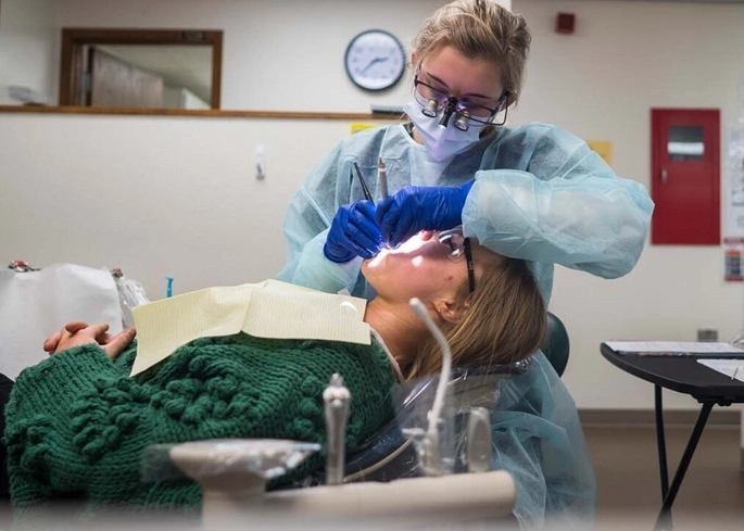 A dental hygiene student works on patient.