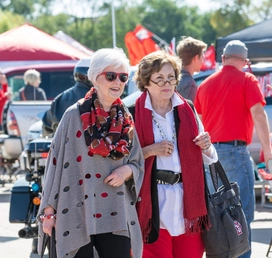 Sue Tuve walking through tailgate with another woman.