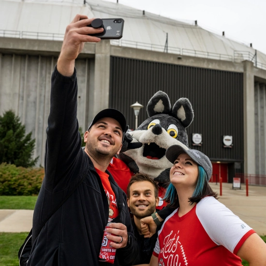 Dakota Days throwback of alum posing with Charlie Coyote at the tailgate