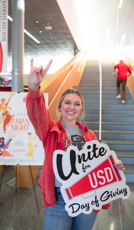Student posing with Unite for USD Giving Day sign