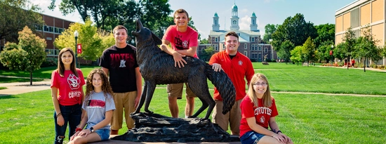Six of the 2018 Coyote Legacy Scholarship recipients pose with the Legacy statue on USD's campus.