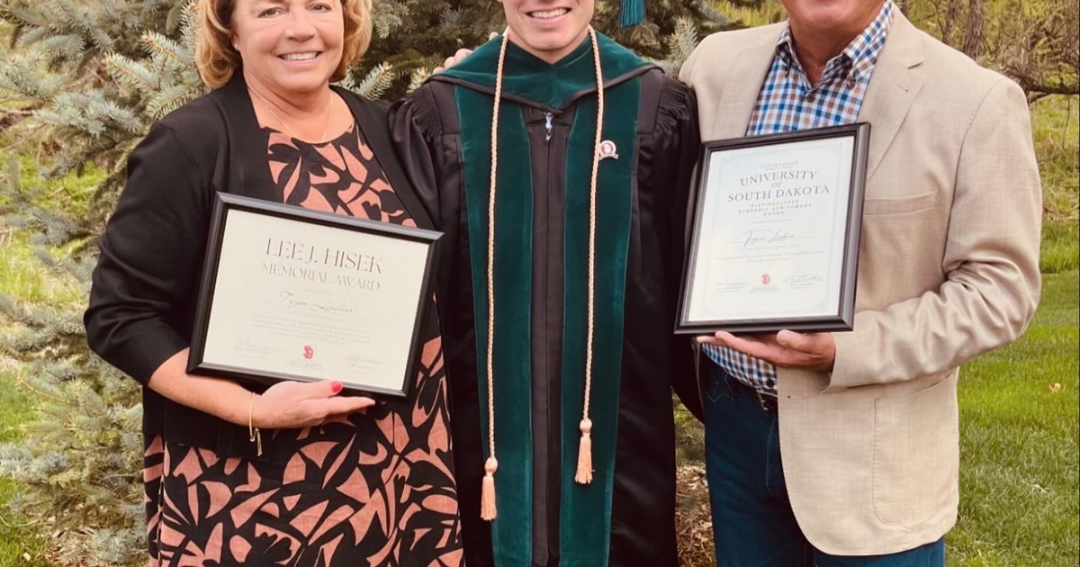 A picture of the Linder family standing in front of a tree at a graduation ceremony.