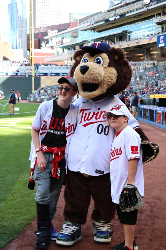 Two boys pose with the Twins mascot
